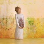 Willow Tree Gracious, 5.5" hand-painted standing resin figure in cream dress, holding pierced-metal pineapple, in front of light orange painting