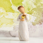 Willow Tree Keepsake, 5.5”h hand-painted standing resin figure in cream dress, holding gold-leaf heart against chest, in front of light green painting