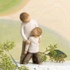 Willow Tree Brothers, 5"h hand-painted resin figure of two boys, younger leaning against older, both dressed in neutral colors, in front of green painting