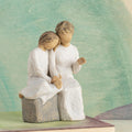 Willow Tree With my Grandmother, 5.5" hand-painted resin figure of older woman seated on gray bench, holding hands with young girl, both in cream dresses, in front of muted green painting