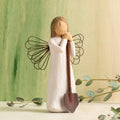 Willow Tree Angel of the Garden, 5.5”h hand-painted standing resin figure in cream dress with wire wings, leaning against brown metal shovel, in front of green painting