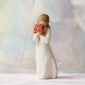 Willow Tree Surrounded by Love, 5"h hand-painted standing resin figure in cream dress, holding large bouquet of red-orange poppies up to face, in front of pastel painting