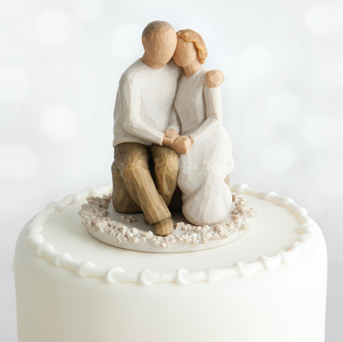 Willow Tree Anniversary Cake Topper, 4”h hand-painted resin figure of seated older couple on bench, holding hands, both in neutral colors, affixed to 3.5" diameter food-safe base of carved white flowers