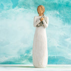 Willow Tree Hero, 9.5”h hand-painted standing resin figure in cream dress holding folded American flag in her arms,  in front of aqua painting