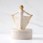 Front view: oval resin box, with 3-D figure in cream and gold carved dress atop lid