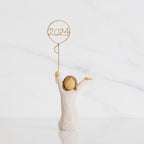 Front view: standing figure in cream dress, arms raised, holding gold wire balloon with 2024 written in gold wire inside