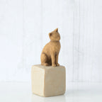 Golden cat figurine sitting on white rock