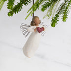 Front view: Darker-skin Angel with wire wings holding red heart. Hook and loop