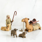 Set of figurines - golden camel laying down surrounded by two grey sheep and wiseman petting golden lamb