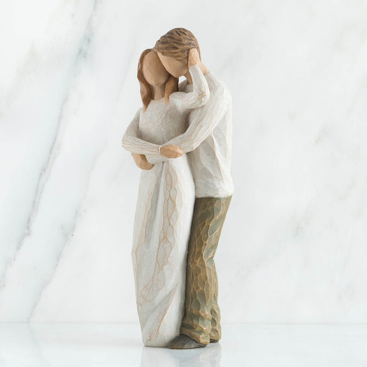 Man and woman couple figurines in white hugging another