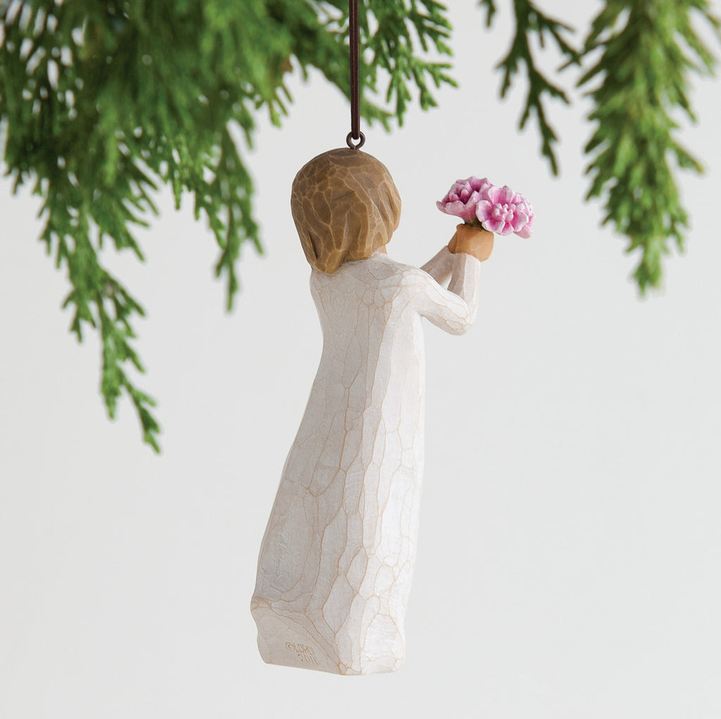 Back view of woman ornament with short brown hair, holding out a bouquet of pink flowers. Brown string attached to top of ornament