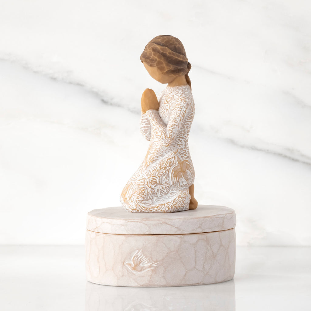 Left side: cream oval resin box, 3-D figure in prayer pose atop lid, in cream dress carved with birds and flowers