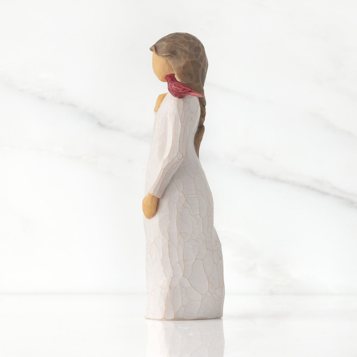 Left side of standing figure in cream dress with cardinal red bird perched on shoulder