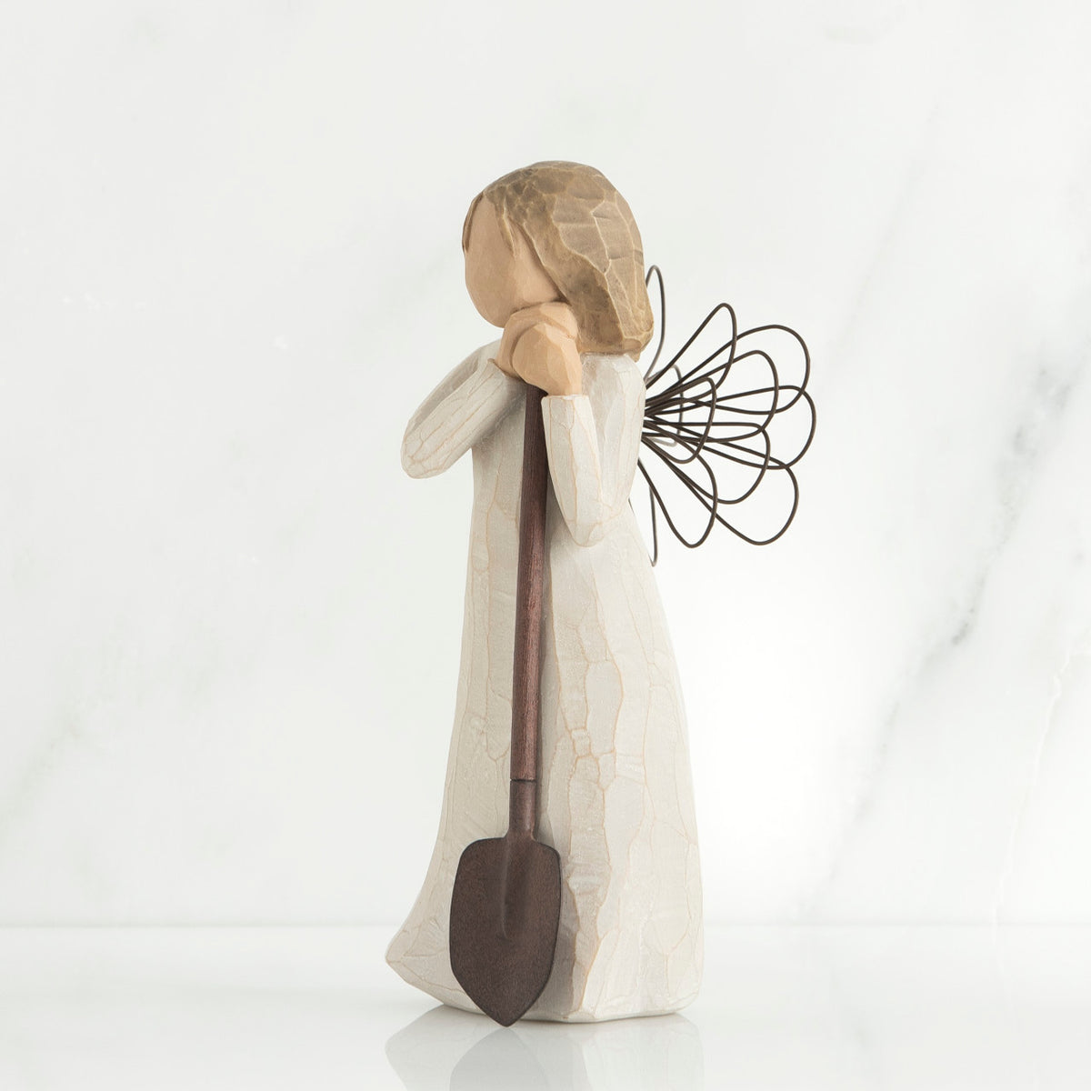 Young brunette girl figurine in white dress holding brown shovel