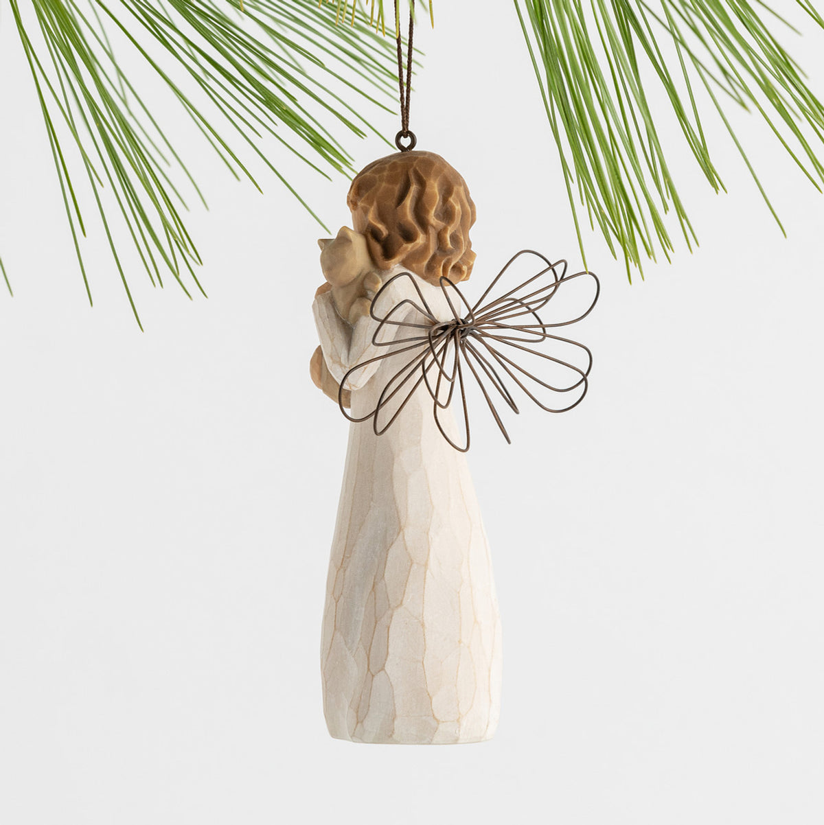 Side view figure in cream dress with wire wings, holding gray cat in arms, ornament loop attached to head