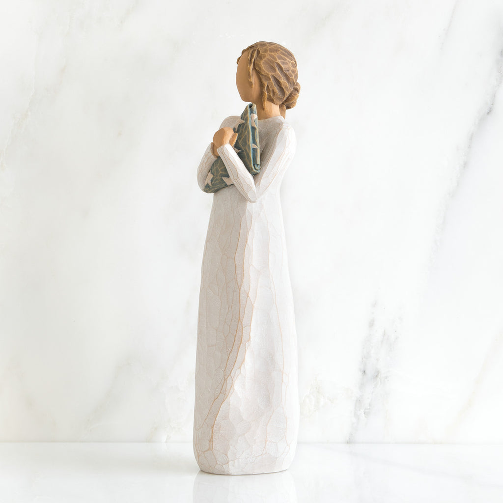 Side view of brunette girl figurine in white dress holding triangle figurine