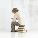 Back view of brunette man figurine in white shirt and blue jeans sitting on books reading a book