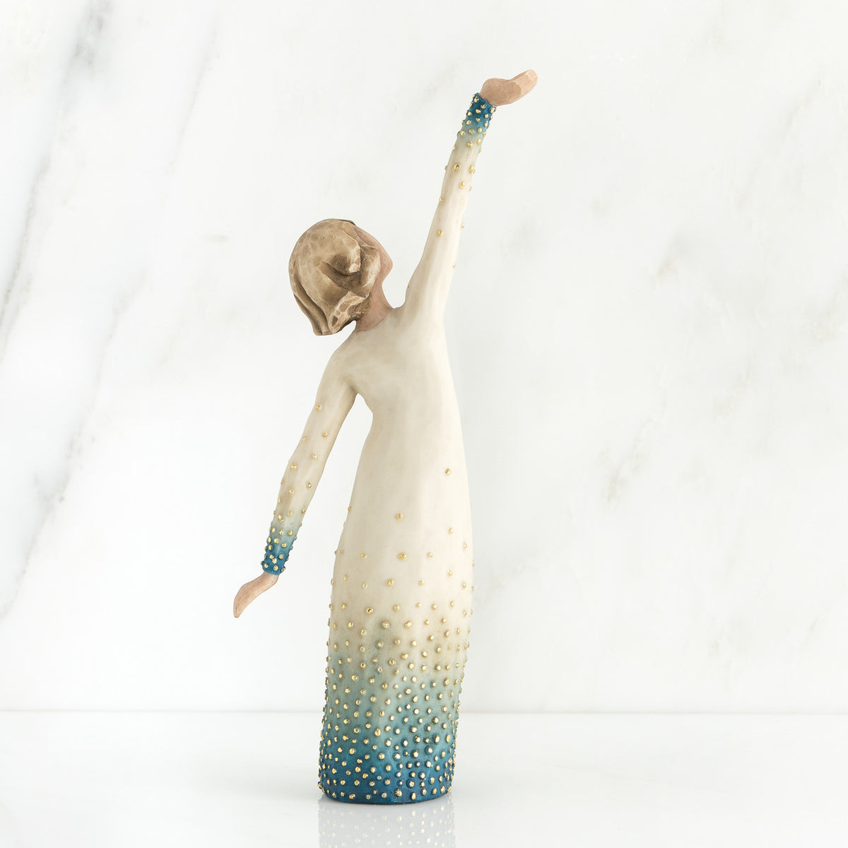 Girl figurine in white dress with blue bottom facing the back with her arms spread