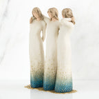 Three brown haired woman figurines with white dresses and blue bottoms with arms on each other
