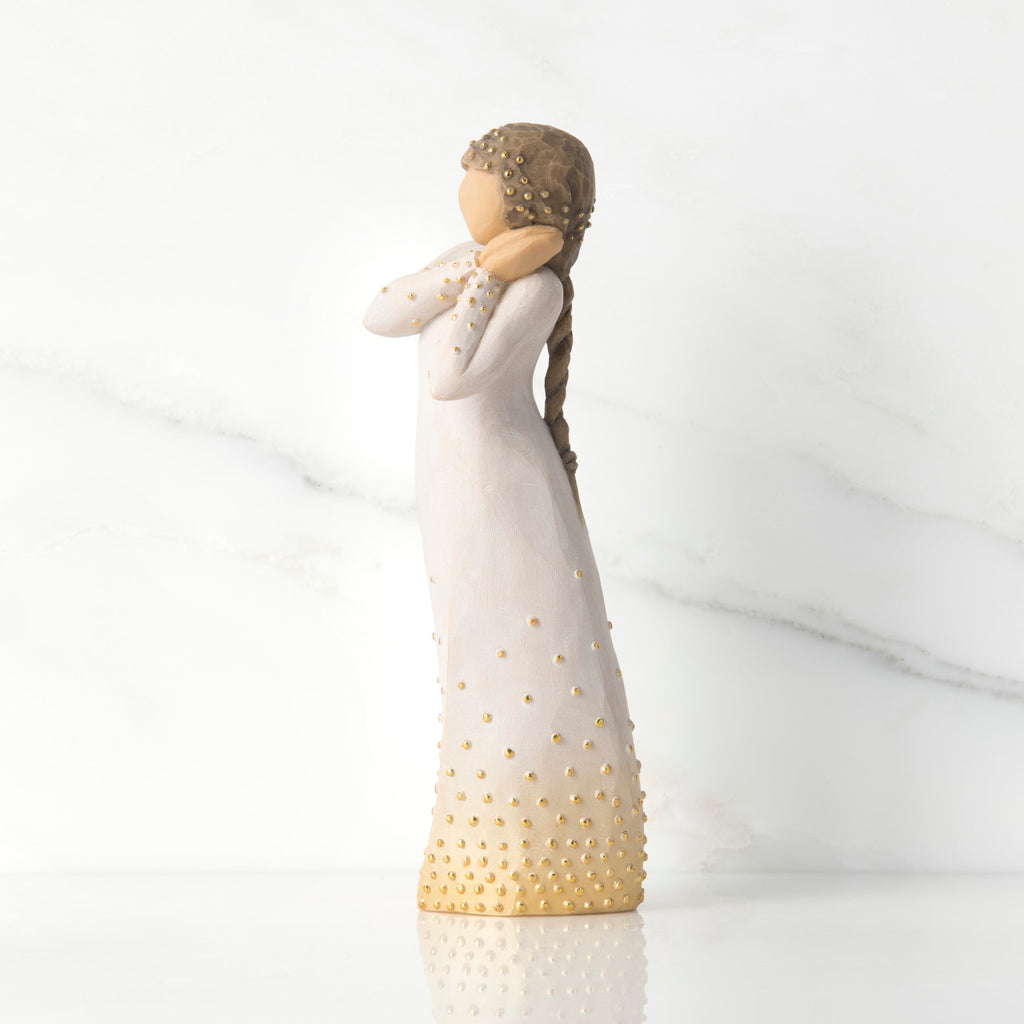 Left-faicng view, standing figure in cream dress, holding arms to face in wistful gesture. Hair and dress embellished with gold dots