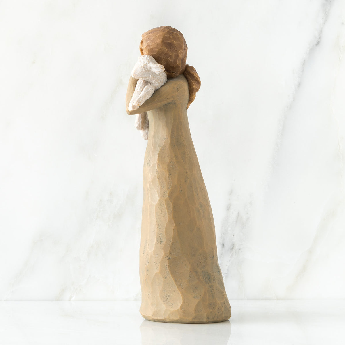 Side view of brunette girl figurine in brown dress holding up sheep figurine