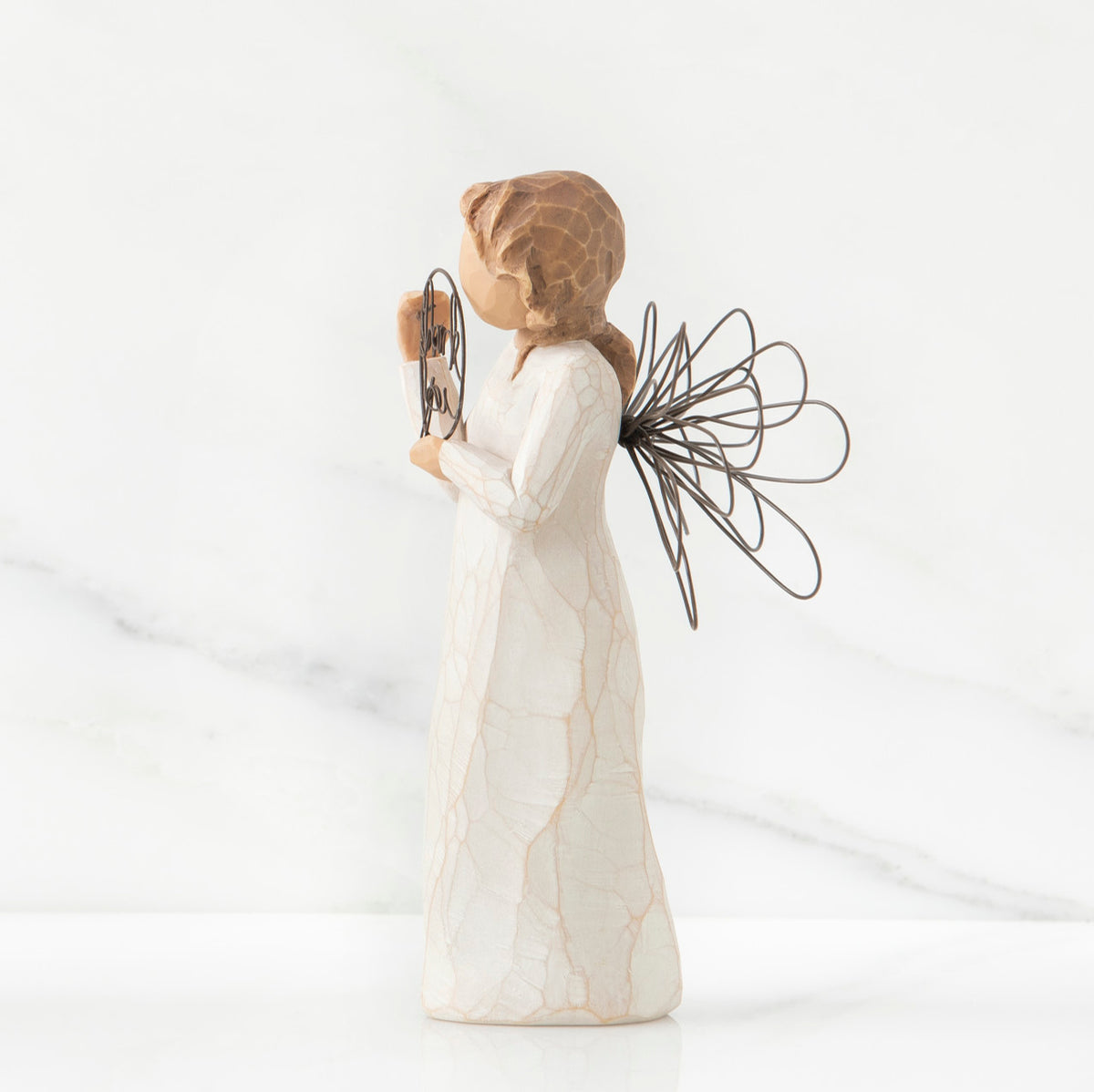 Right side view of angel with tied back brown hair, holding up a circular wire sign that says "thank you"