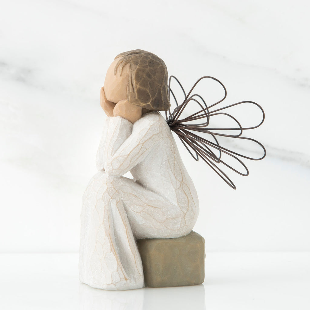 Right side view of angle with brown hair sitting on a stone with her hands cupping her cheeks