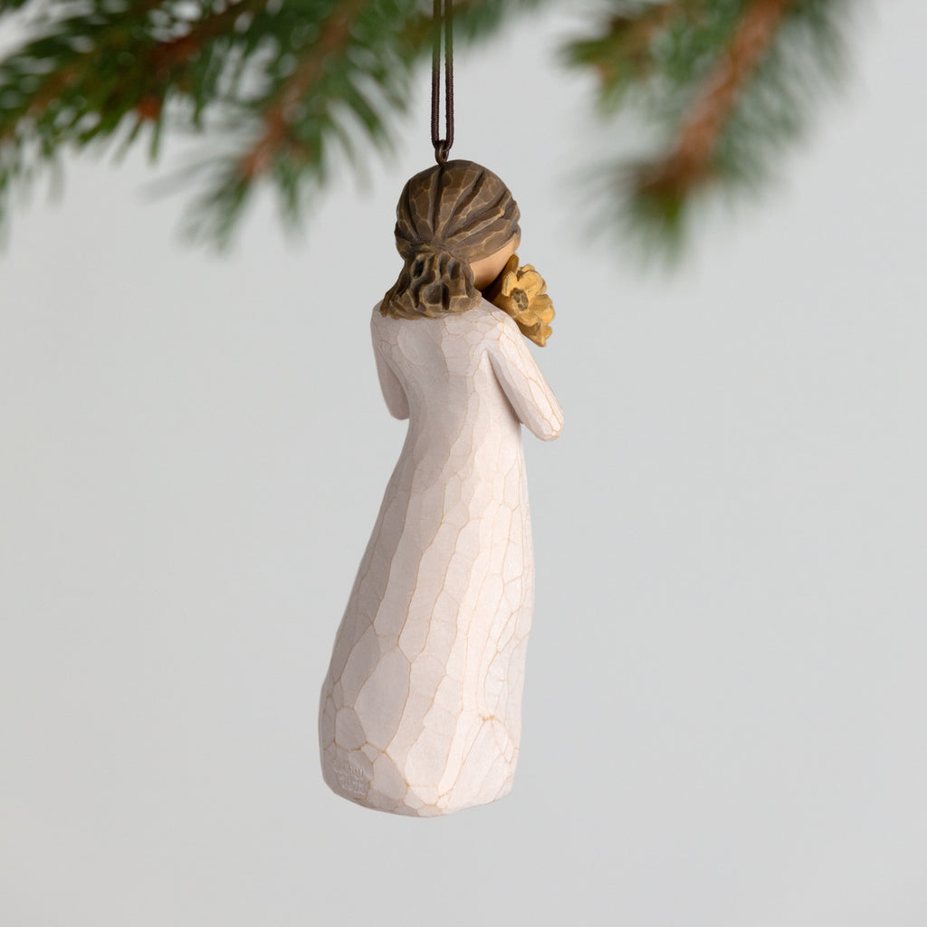 Back view of female figure ornament in cream dress, holding large bouquet of yellow sunflowers up to face
