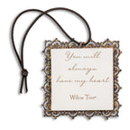 Small square bas-relief carving of boy holding gold heart, edged in pierced-metal filigree with brown elastic ornament loop