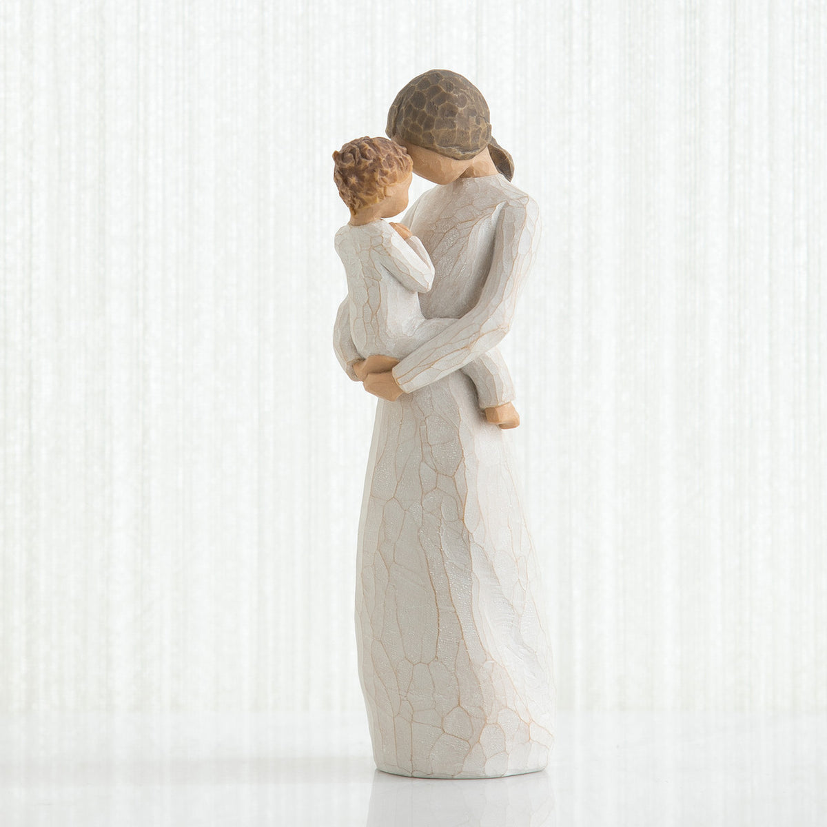 Mother figurine in white dress with brunette hair holding baby in white