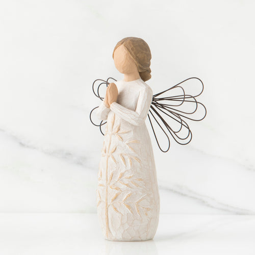 Side view of brunette angel figurine in white dress holding hands in prayer with black wire wings