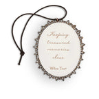 Back of small oval ornament with sentiment written in script on cream, edged in pierced-metal filigree