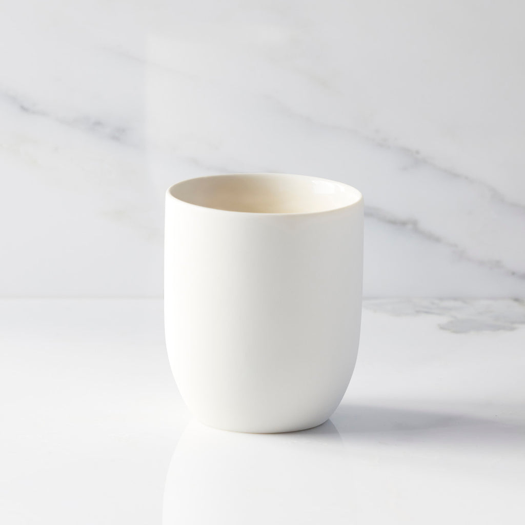 Back view of unglazed off-white tapered cylinder ceramic candle vessel