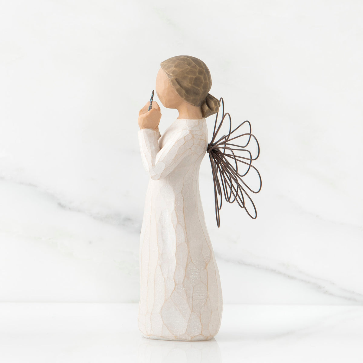 Side view of young brunette girl figurine in white dress with brown wire wings standing