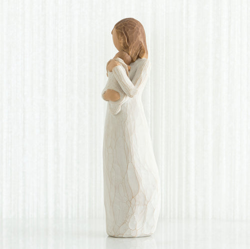 Side view of brunette girl figurine in white dress holding baby