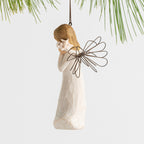 Side view female angel with wire wings in cream dress, holding pink shell up to ear, ornament loop attached to head