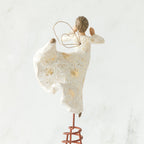 Brunette angel figurine facing away from camera in white dress, gold wings, and dancing on red stand with arms out