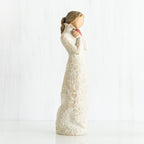 Side view of brunette girl figurine in white dress holding pink hear figurine