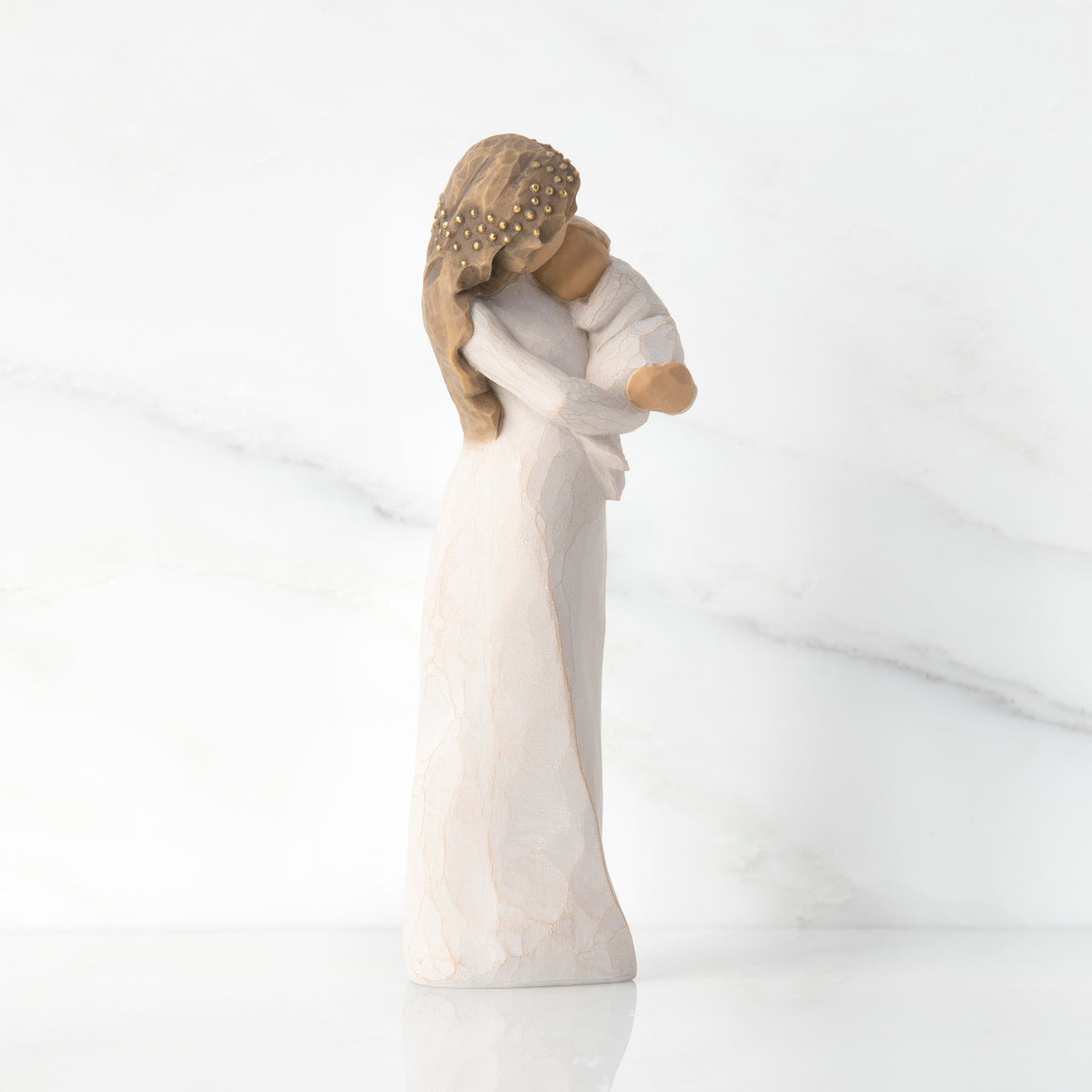 Side view of brunette woman figurine in white dress holding swaddled baby