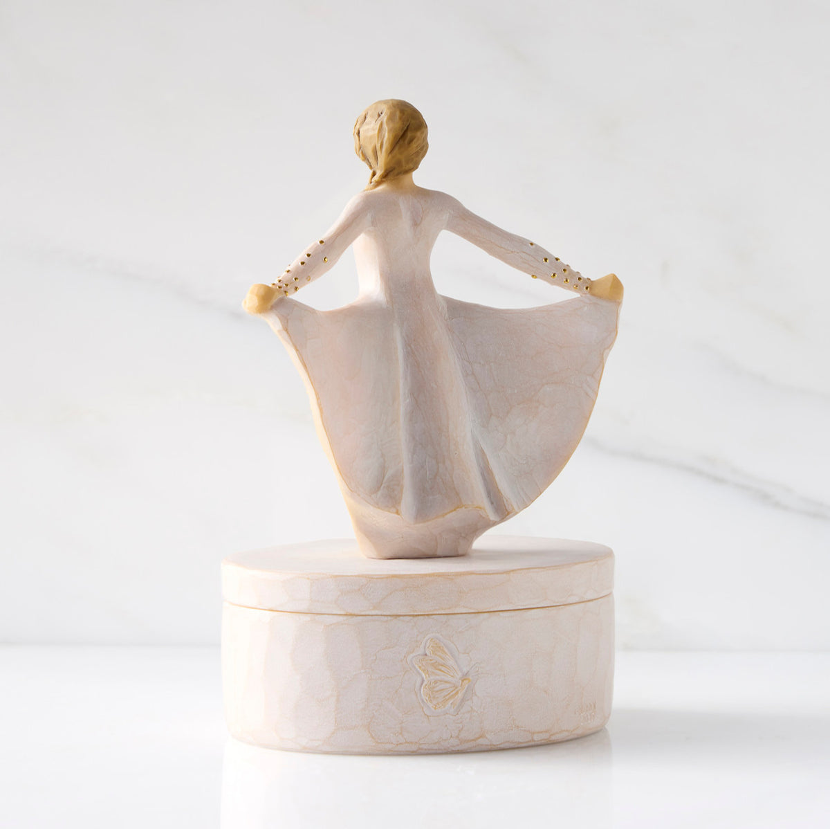 Back view: oval resin box, showing back of 3-D figure in cream dress atop lid