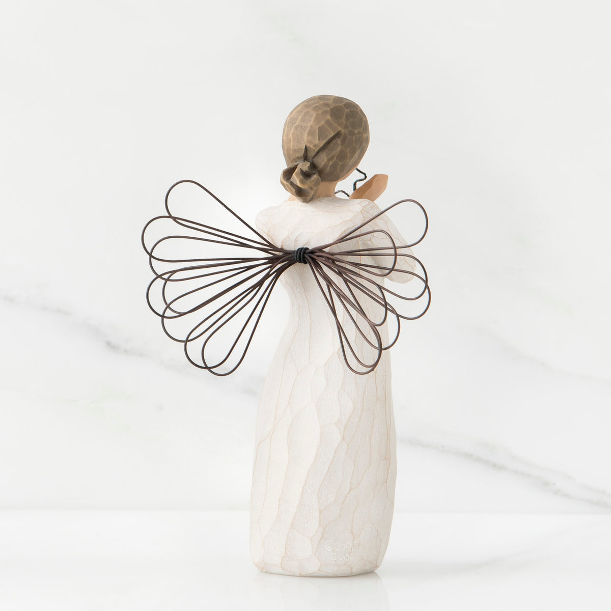 Back view of angel figurine in white dress with brown wire wings