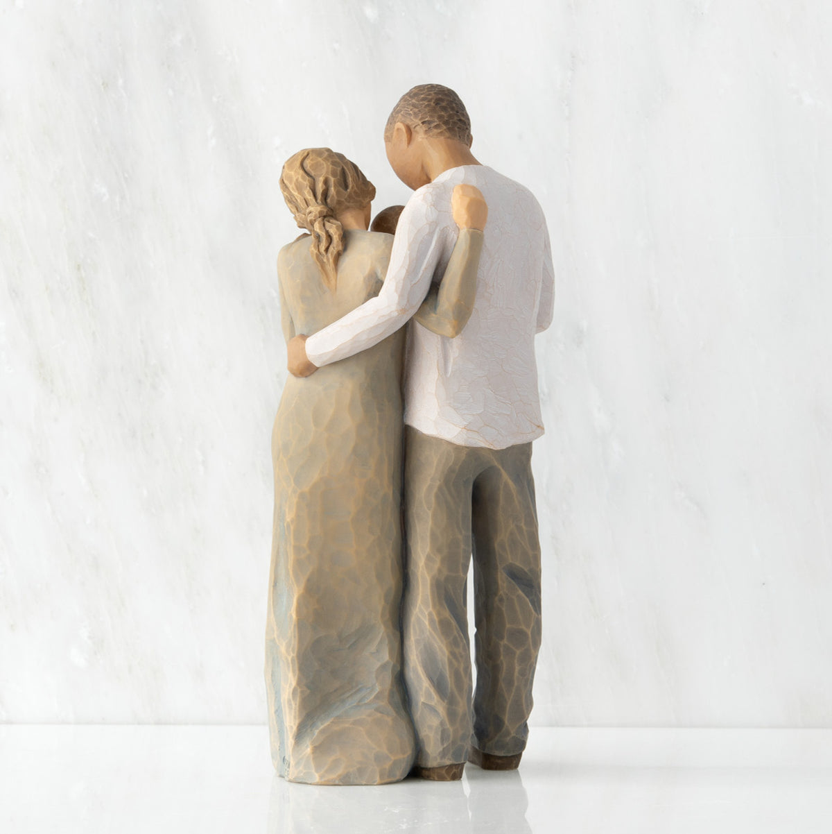 Back view of standing couple, woman has lighter skin and hair; man has darker skin and hair, holding a baby between them.