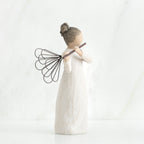 Side view of brunette girl angel figurine in white dress playing flute