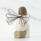 Back view of angle with brown hair sitting on a stone with her hands cupping her cheeks