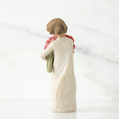 Back view of brunette woman figurine in white dress holding flowers