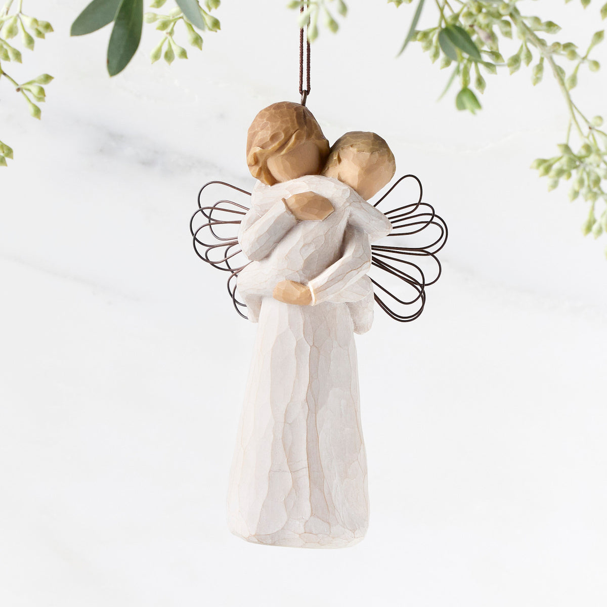 Figure of female in cream dress with wire wings, holding baby in cream onesie, with ornament loop on head