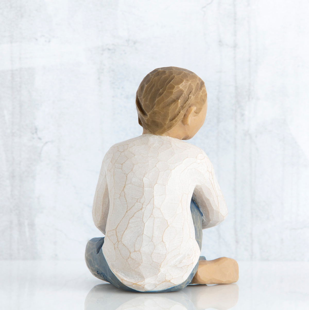 Back view of boy figurine sitting wearing white shirt