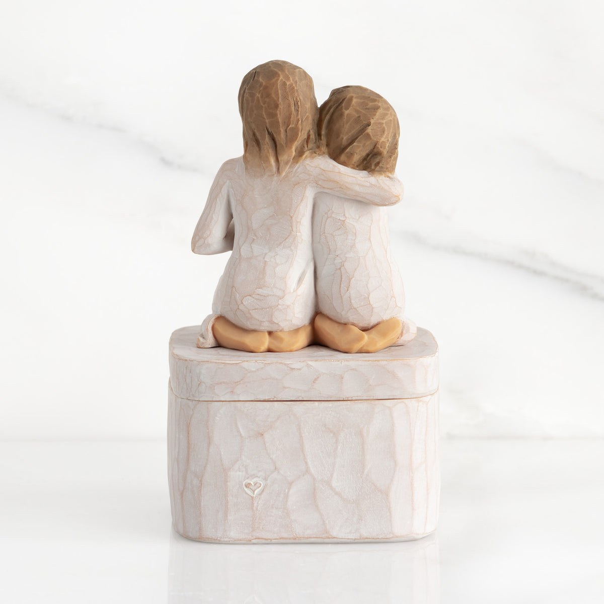 Back view showing heart carved into square resin box base: back view of two 3-D figures kneeling atop lid