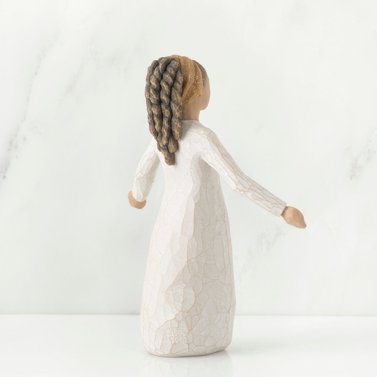 Back view of brunette girl figurine in white dress holding her hands out