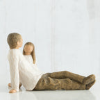 Man and woman figurine in white with brown pants sitting looking at one another